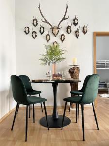 stół jadalny z zielonymi krzesłami i porożami na ścianie w obiekcie NEU! Magic Forest Design-Luxus-Apartment, am Markt, Garten w mieście Gera