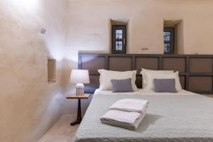 Un dormitorio con una cama grande con lámpara y almohadas. en Lethos Villa - Tinos, en Kionia 97 fotos más