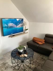 ein Wohnzimmer mit einem Sofa und einem TV an der Wand in der Unterkunft Sobe VaLux Valpovo in Valpovo