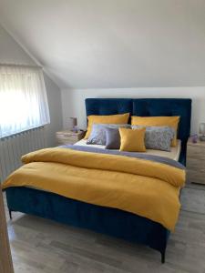 sypialnia z dużym łóżkiem z żółtą i niebieską pościelą w obiekcie Sobe VaLux Valpovo w mieście Valpovo