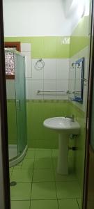 a green bathroom with a sink and a shower at Artan apartment in Vlorë