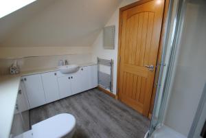 a bathroom with a toilet and a sink and a wooden door at Stronvar- coastal home with sea views in Pittenweem +39 photos