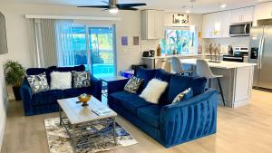 a living room with blue couches and a kitchen at Waterfront Gulf Gateway: Pool/Dock/Grill/Gameroom in Fort Myers