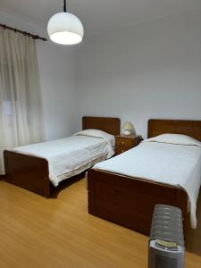 Un dormitorio con dos camas y un banco en él. en Alojamento das Laranjeiras, en Fernao Ferro