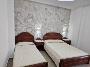 two twin beds in a room with a wall at Emmanouela Studios & Villas in Karterados