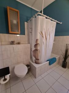 a bathroom with a toilet and a shower curtain at Amselpark in Barkelsby