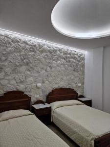 a bedroom with two beds and a stone wall at Emmanouela Studios & Villas in Karterados