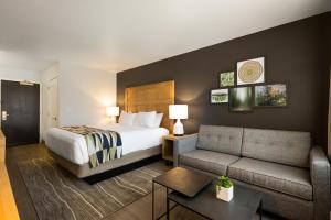 a hotel room with a bed and a couch at Oxford Suites Redding in Redding