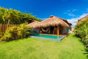 a villa with a swimming pool and a hut at Pousada Tatuá in Pôrto de Pedras