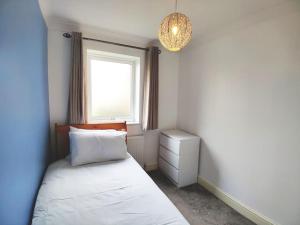 a bedroom with a bed and a window and a chandelier at Cosy and modern two bedroom flat near Heathrow in Hayes