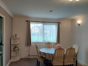 a dining room with a table and chairs and a window at Cosy and modern two bedroom flat near Heathrow in Hayes