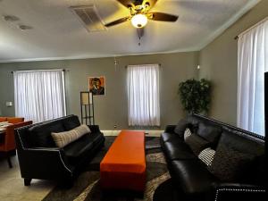 sala de estar con muebles de cuero negro y ventilador de techo en Renovated,Comfortable and Convenient Experience, en Rocky Mount