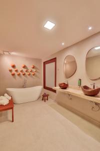 y baño con bañera, lavabo y espejos. en Pousada Tatuá, en Porto de Pedras