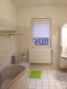 a bathroom with a tub and a toilet and a window at Duc Anh Ferienwohnung in Emden