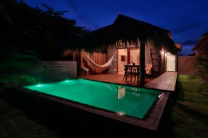 a swimming pool in front of a house at night at Pousada Tatuá in Pôrto de Pedras