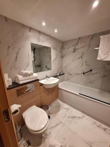 a bathroom with a toilet and a sink and a tub at Five Lamps Suites in Dublin