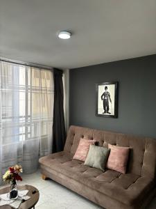 a living room with a brown couch with pink pillows at Cómodo apartamento en la Villa Olímpica de Pereira in Pereira