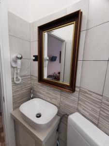 a bathroom with a sink and a mirror and a toilet at Affittacamere Sciacchithouse in Florence