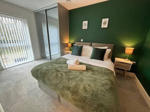 a bedroom with a large bed with a green wall at Luxury Canal-side Apartment, Hemel Hempstead, Free parking, Perfect for Contractors in Hemel Hempstead