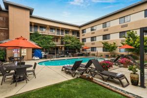 a courtyard with a swimming pool with chairs and umbrellas at Oxford Suites Redding in Redding