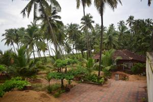 a house in the middle of a bunch of palm trees at BEACH faceing rooms with private beach in Kalyānpur +34 photos
