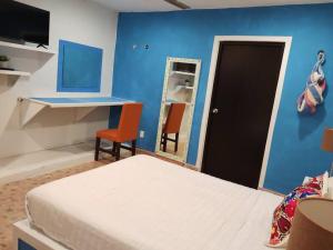 1 dormitorio con cama y pared azul en T´úubul K´iin Bed & Breakfast, en Mérida