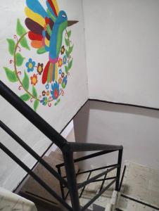 een stoel met een kleurrijke vogel op de muur geschilderd bij T´úubul K´iin Bed & Breakfast in Mérida
