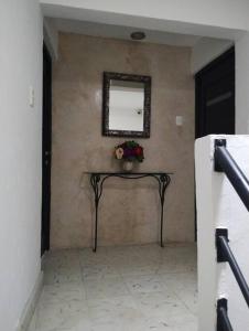 a hallway with a table with a mirror and flowers at T´úubul K´iin Bed & Breakfast in Mérida