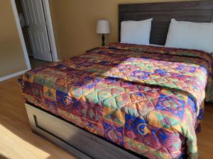 a bedroom with a bed with a colorful quilt at Elks Motel in Keremeos