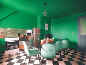 a kitchen with green walls and a table and chairs at Grand Appartement 8 personnes - parking gratuit in Mulhouse