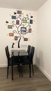a table with chairs and a tree with pictures on a wall at Perfect flat next to Wembley Stadium in London