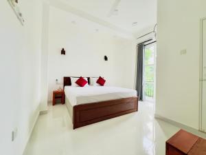 a white bedroom with a bed and a window at Lavish Weligama in Weligama