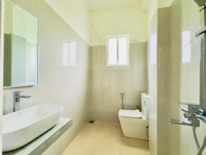 Baño blanco con lavabo y aseo en Lavish Weligama, en Weligama