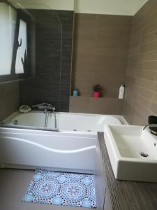 ein Badezimmer mit einer weißen Badewanne und einem Waschbecken in der Unterkunft Mina’s Villa, 200m from the beach in Porto Rafti