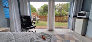 a room with a bed and a chair and a window at Island Flip Flop Holidays in Sedgefield