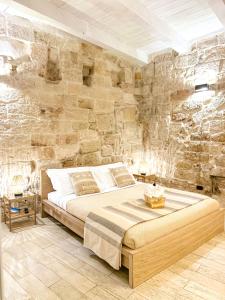 una camera con un grande letto in una parete in pietra di Old tuff apartments a Polignano a Mare