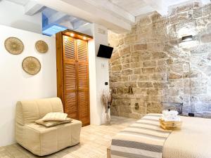 una camera con un letto, una sedia e un muro in pietra di Old tuff apartments a Polignano a Mare