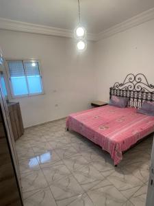 a bedroom with a bed with a pink comforter at DIaR MAHER in Al Maqārisah