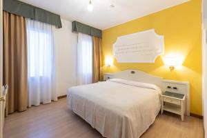 a bedroom with a white bed and a yellow wall at Hotel Ca' Tron in Dolo