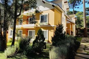 a yellow house with trees in front of it at Apto Elegance Bairro Nobre, junto a Natureza in Canela