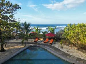 a swimming pool with chairs and umbrellas and the ocean at Sunset Waves House in San Diego