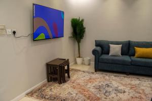 شقة مخدومه مفروشة قباء 303 في المدينة المنورة: غرفة معيشة مع أريكة وتلفزيون على الحائط