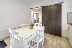Santa Rita Greenhouse Villas في بونتا ديلغادا: غرفة طعام بيضاء مع طاولة زجاجية وكراسي بيضاء