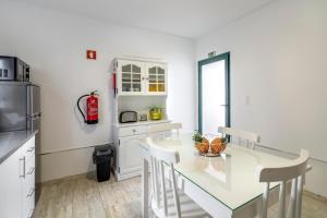 una cucina con tavolo, sedie e frigorifero di Santa Rita Greenhouse Villas a Ponta Delgada