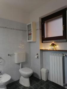 a bathroom with a toilet and a tv on the wall at Appartamento con terrazza e giardino in Val d'Intelvi in Lanzo dʼIntelvi