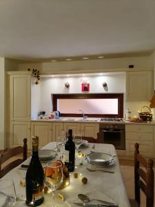a kitchen with a table with wine bottles and glasses at Appartamento con terrazza e giardino in Val d'Intelvi in Lanzo dʼIntelvi