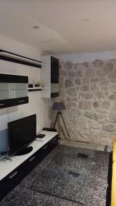 uma sala de estar com televisão e uma parede de pedra em Le first em Grasse