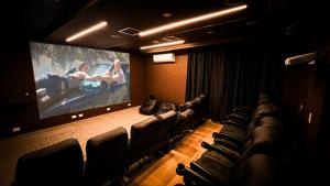 a cinema room with a large screen with a movie at Catalina Hotel in Ubatuba