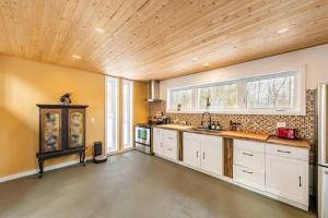 a kitchen with white cabinets and a wooden ceiling at Cozy and beautiful chalet in Harrington