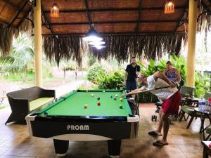 a man playing a game of pool on a pool table at Mango Home Riverside in Ben Tre